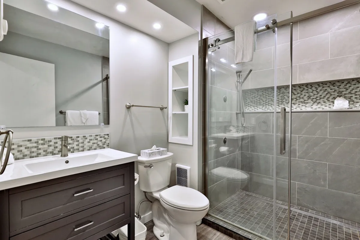 A bright and inviting bathroom featuring a double sink vanity, glass shower enclosure, and decorative tiles. The space is fresh and elegant, evoking a spa-like atmosphere perfect for unwinding after a day of adventure.