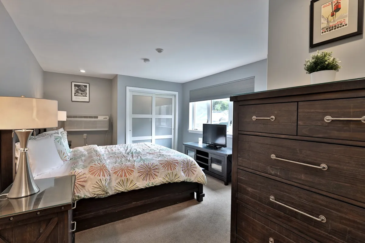 A cozy bedroom scene with a decorative bed, dresser, and television. Soft lighting and plush bedding create a comfortable, inviting environment ideal for snuggling up after a day out. The space exudes warmth and peace, perfect for a romantic escape.